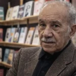 Vedat Türkali’nin kitaplık önünde çekilmiş, renkli ve yazısız portre fotoğrafı