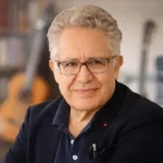 Zülfü Livaneli’nin edebiyat, müzik ve düşünce dünyasındaki üretimlerini çağrıştıran, sade ve doğal portre görseli.