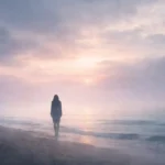 Sisli bir sahilde denize doğru bakan yalnız bir figür ve yumuşak ışıklı ufuk manzarası
